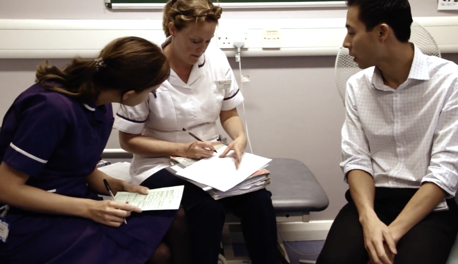 Three healthcare professionals sitting together with paperwork, having a discussion.