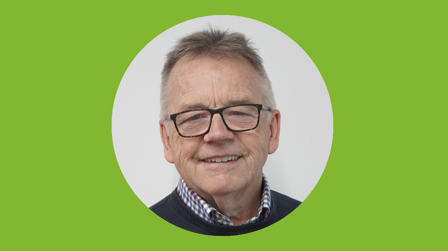 A man with glasses smiles at the camera