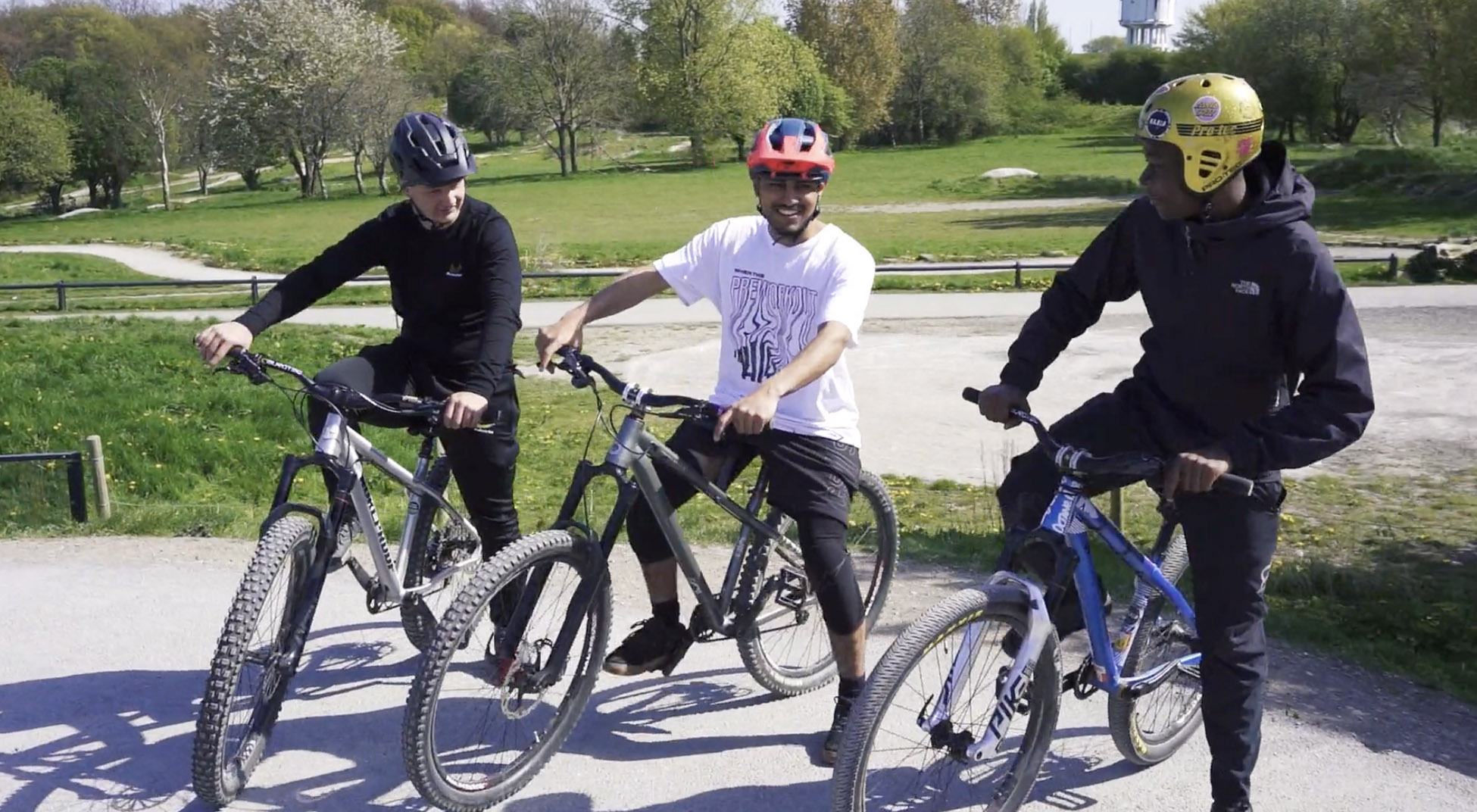 Three teenagers sitting on their bikes, happy.